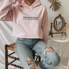 a woman sitting on a chair wearing a pink hoodie