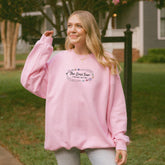 a woman wearing a pink sweatshirt and jeans