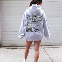 a woman in a white hoodie is standing on a skateboard