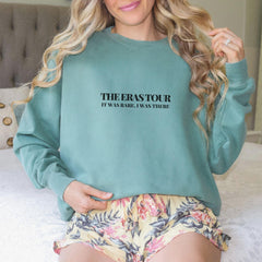 a woman sitting on top of a bed wearing a sweatshirt