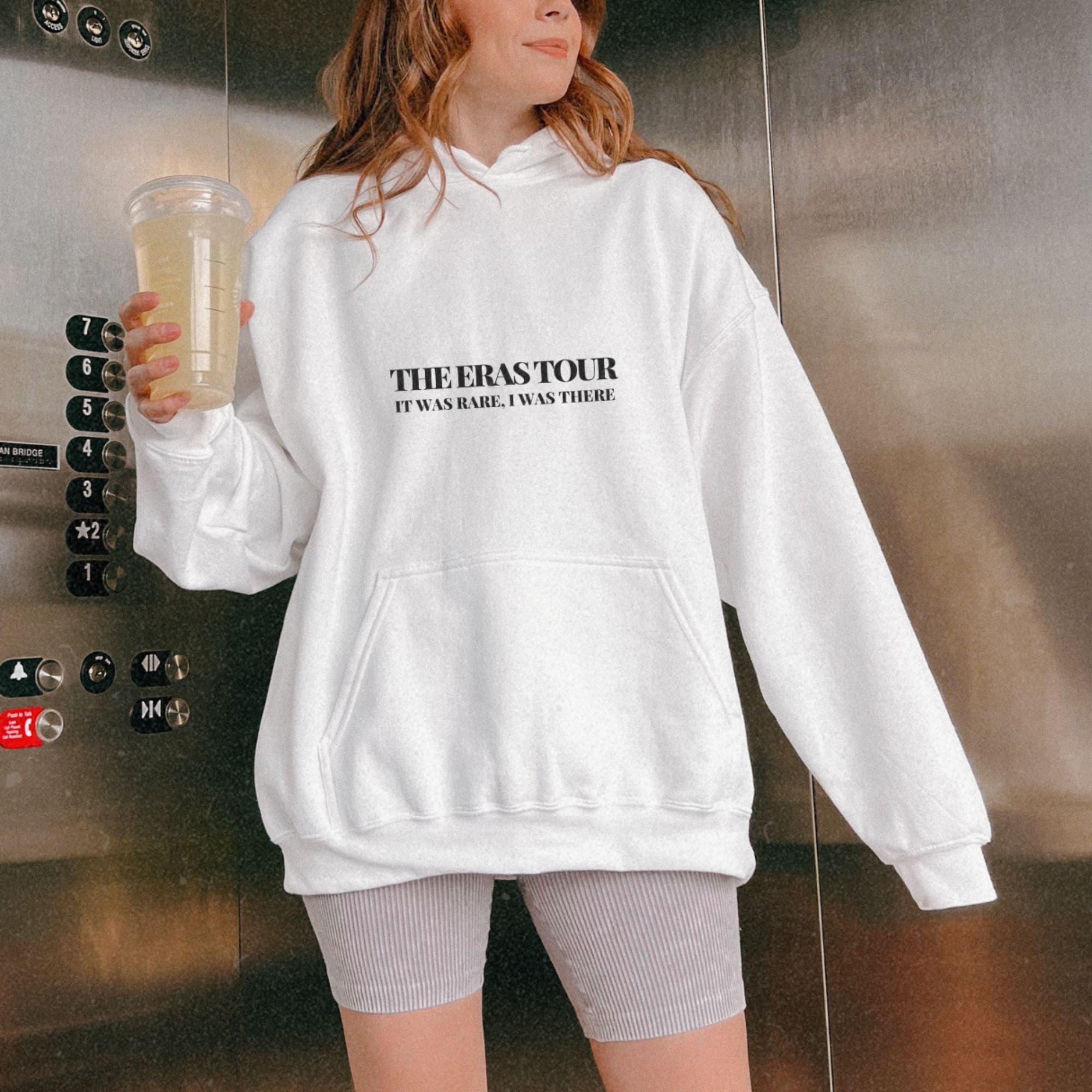a woman in a white hoodie holding a drink