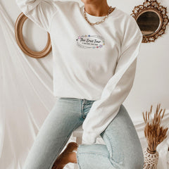 a woman sitting on a stool wearing a white sweatshirt and jeans