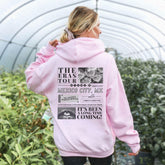 a woman wearing a pink hoodie in a greenhouse
