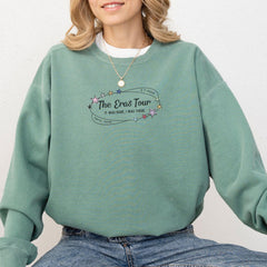 a woman wearing a green sweatshirt with the words the eras tour on it