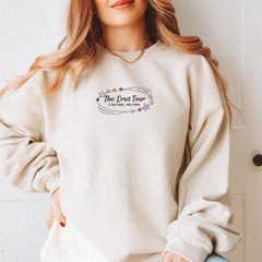 a woman wearing a white sweatshirt with the words the great tour printed on it