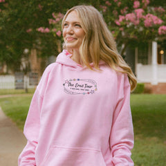 a woman in a pink hoodie is standing on a sidewalk