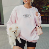 a woman in a pink sweatshirt holding a white dog