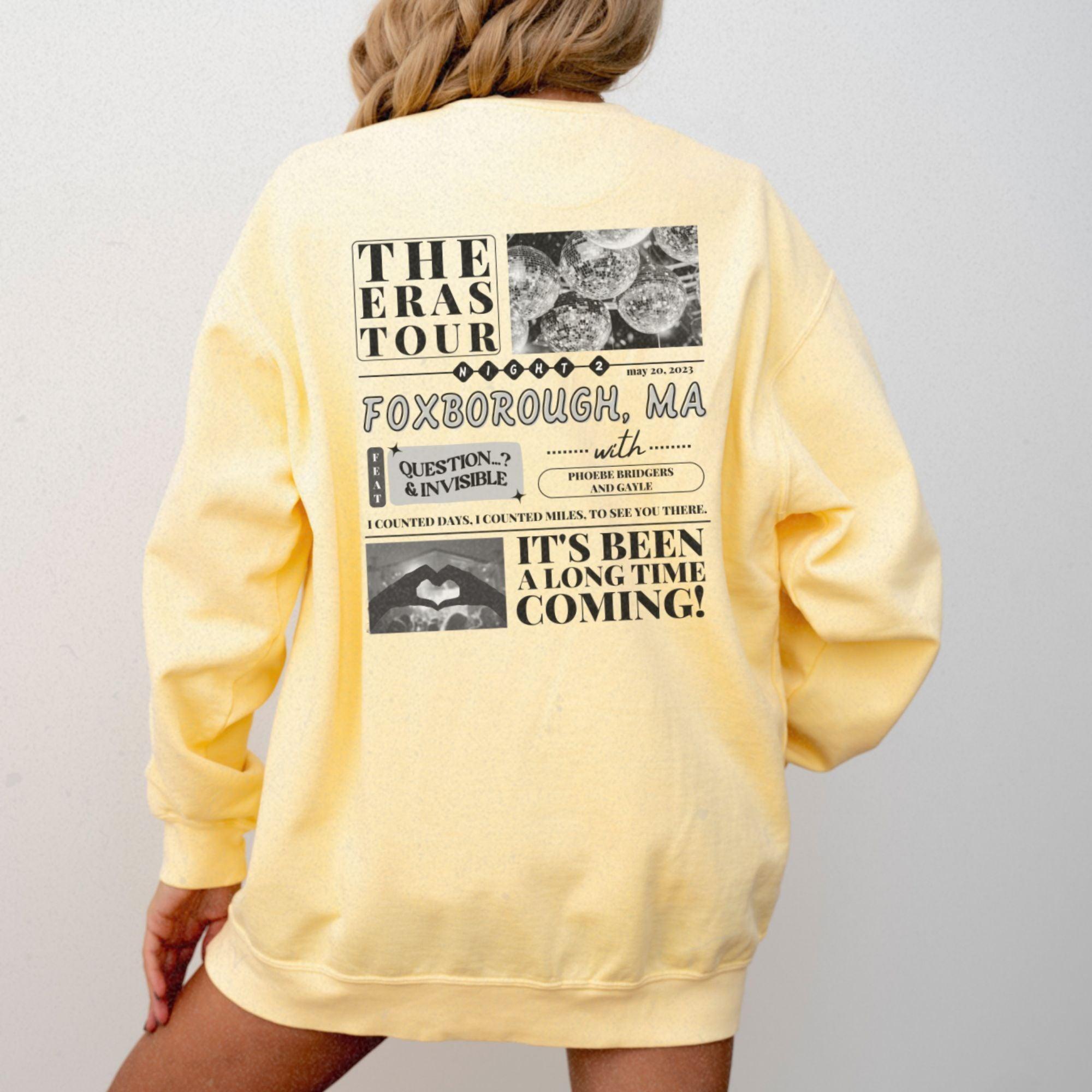 a woman wearing a yellow sweatshirt with the words the eras tour on it