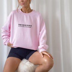 a woman sitting on top of a white dog wearing a pink sweatshirt