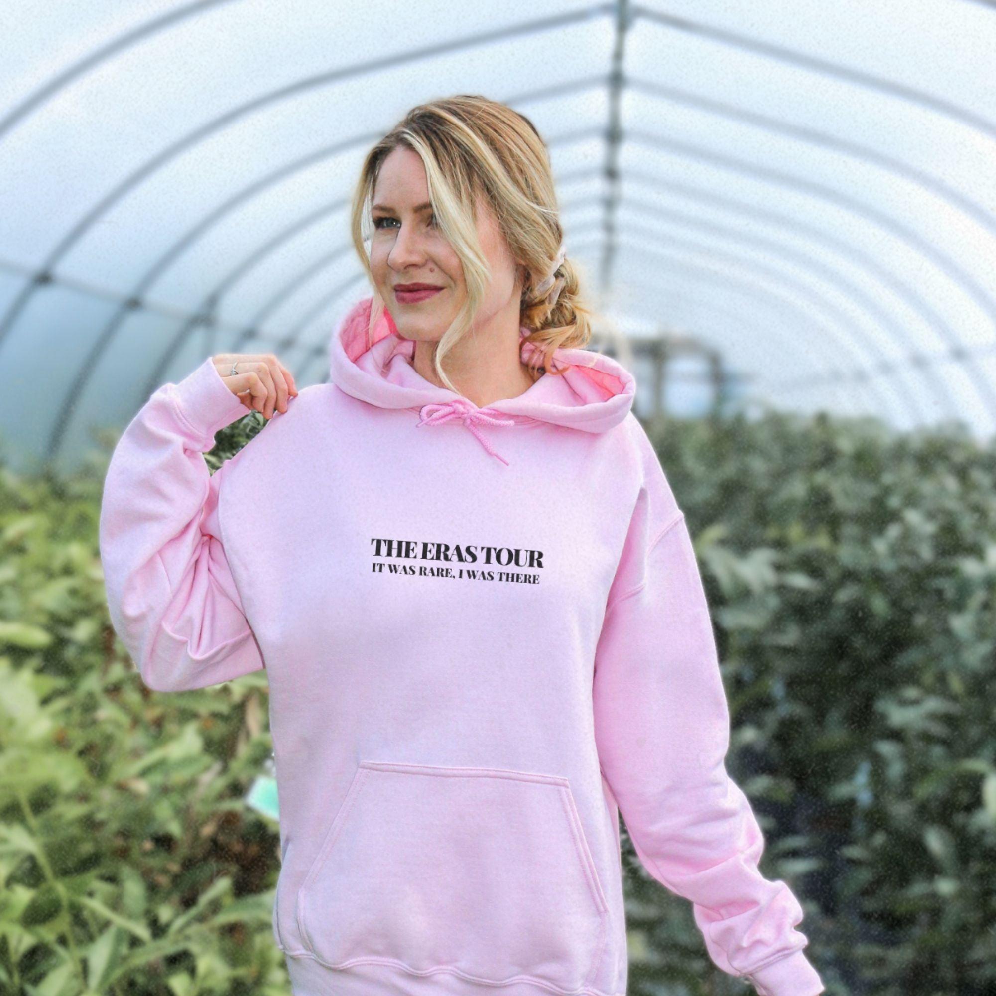 a woman in a pink hoodie is walking in a greenhouse