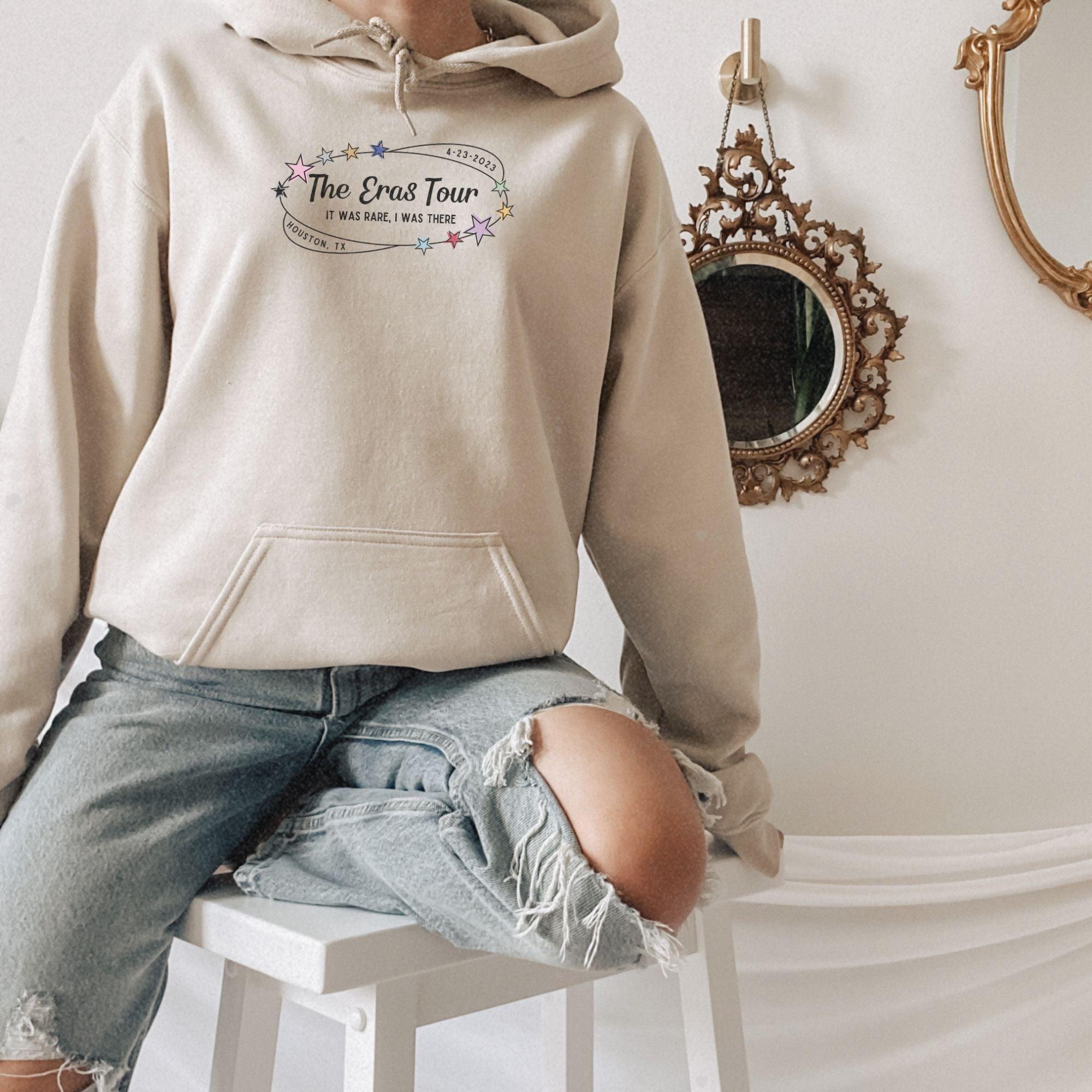 a woman sitting on a stool wearing a hoodie