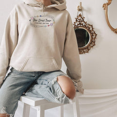 a woman sitting on a stool wearing a hoodie