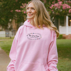a woman in a pink hoodie is standing on a sidewalk