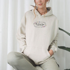 a woman sitting on a stool wearing a white hoodie