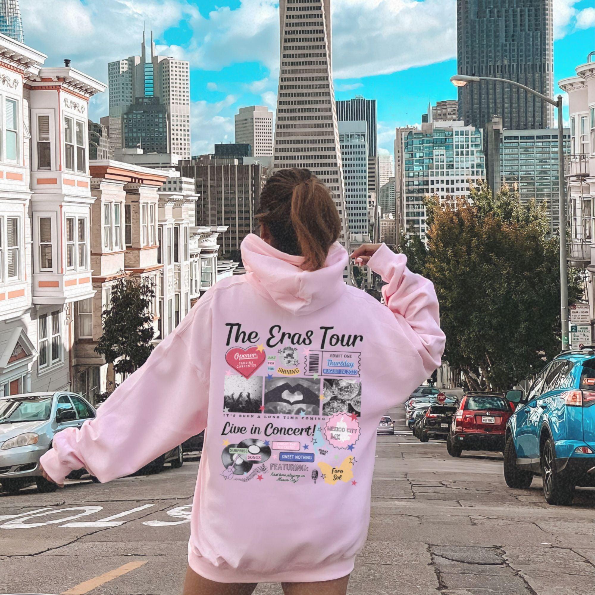 a woman in a pink hoodie walking down a street