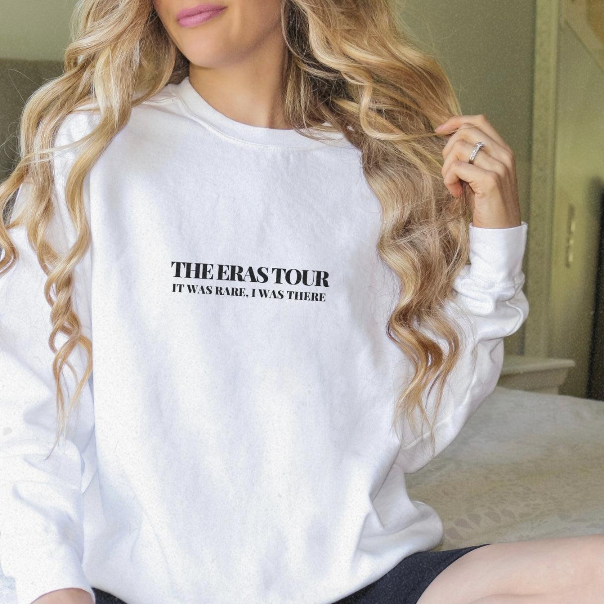 a woman sitting on a bed wearing a white sweatshirt