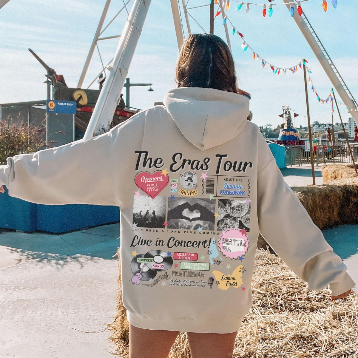 a woman in a white hoodie standing in front of a ferris wheel