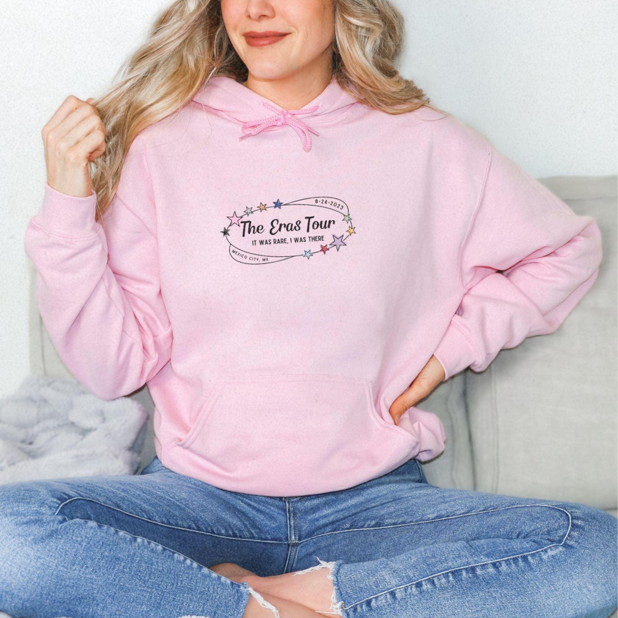 a woman sitting on a couch wearing a pink hoodie