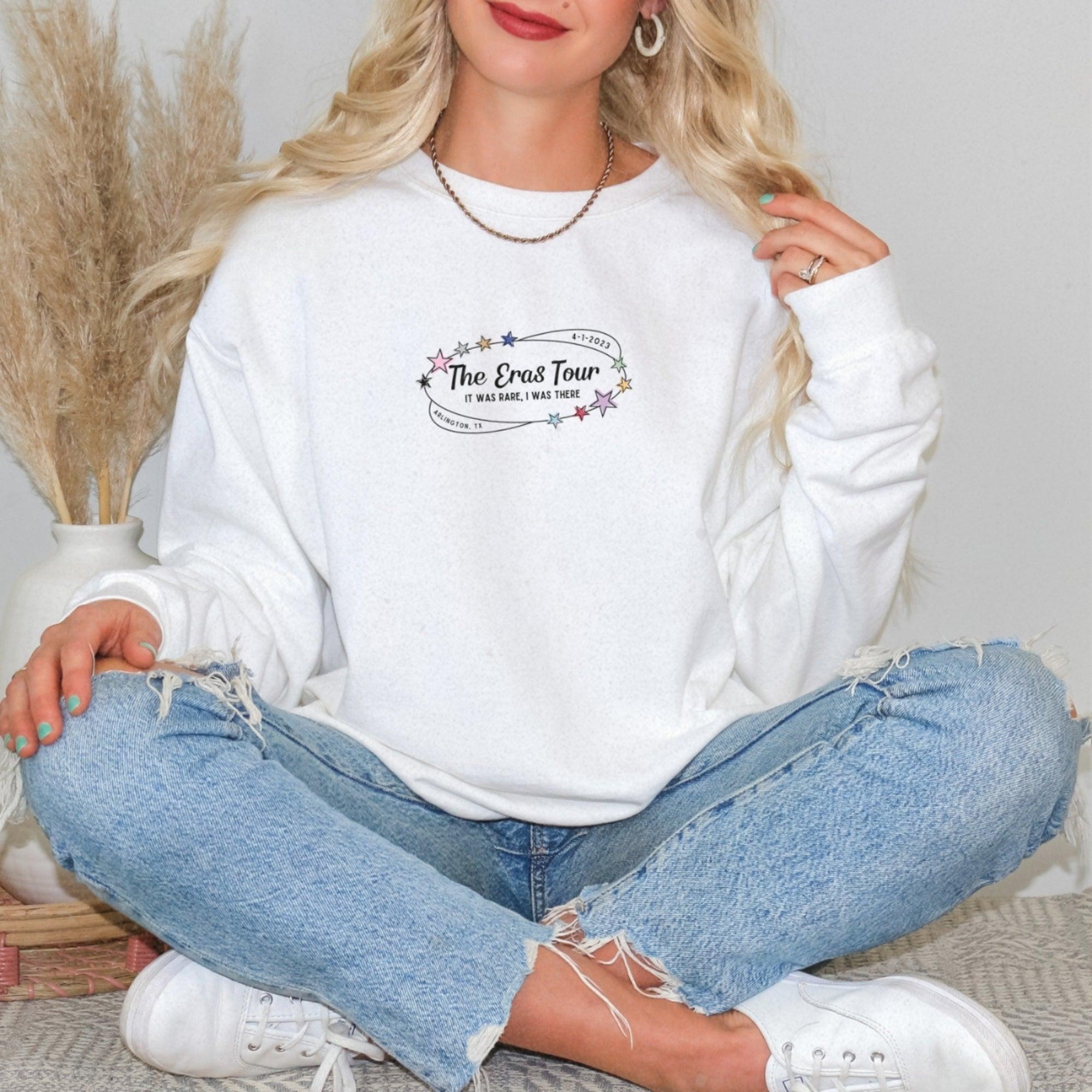 a woman sitting on the floor wearing a white sweatshirt