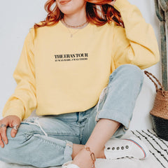 a woman sitting on the floor wearing a yellow sweatshirt
