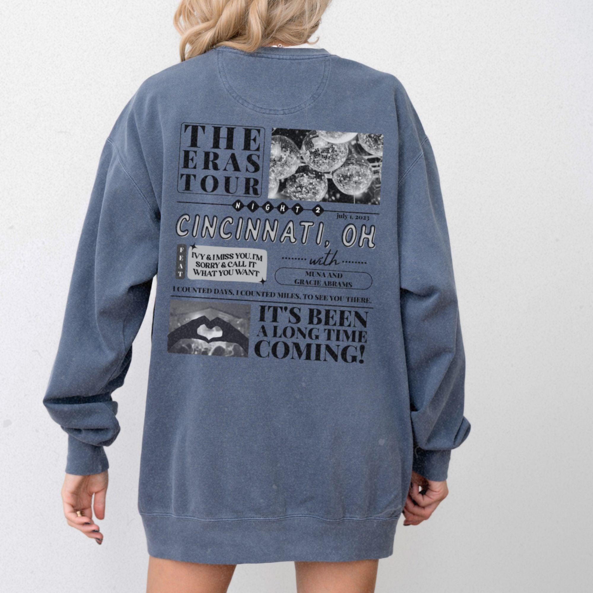 a woman wearing a blue sweatshirt dress with the words the eras tour on it