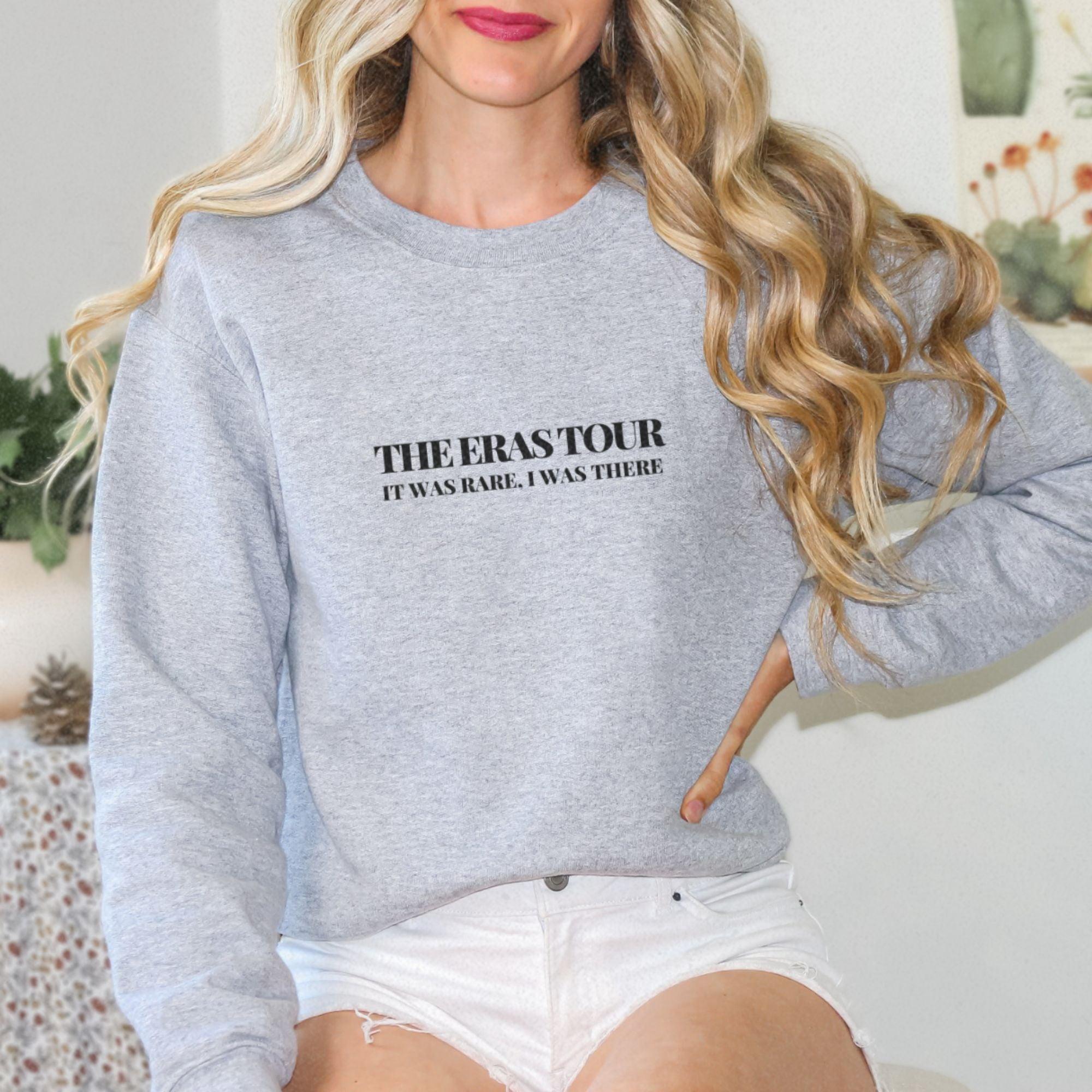 a woman with long blonde hair wearing a grey sweatshirt and white shorts