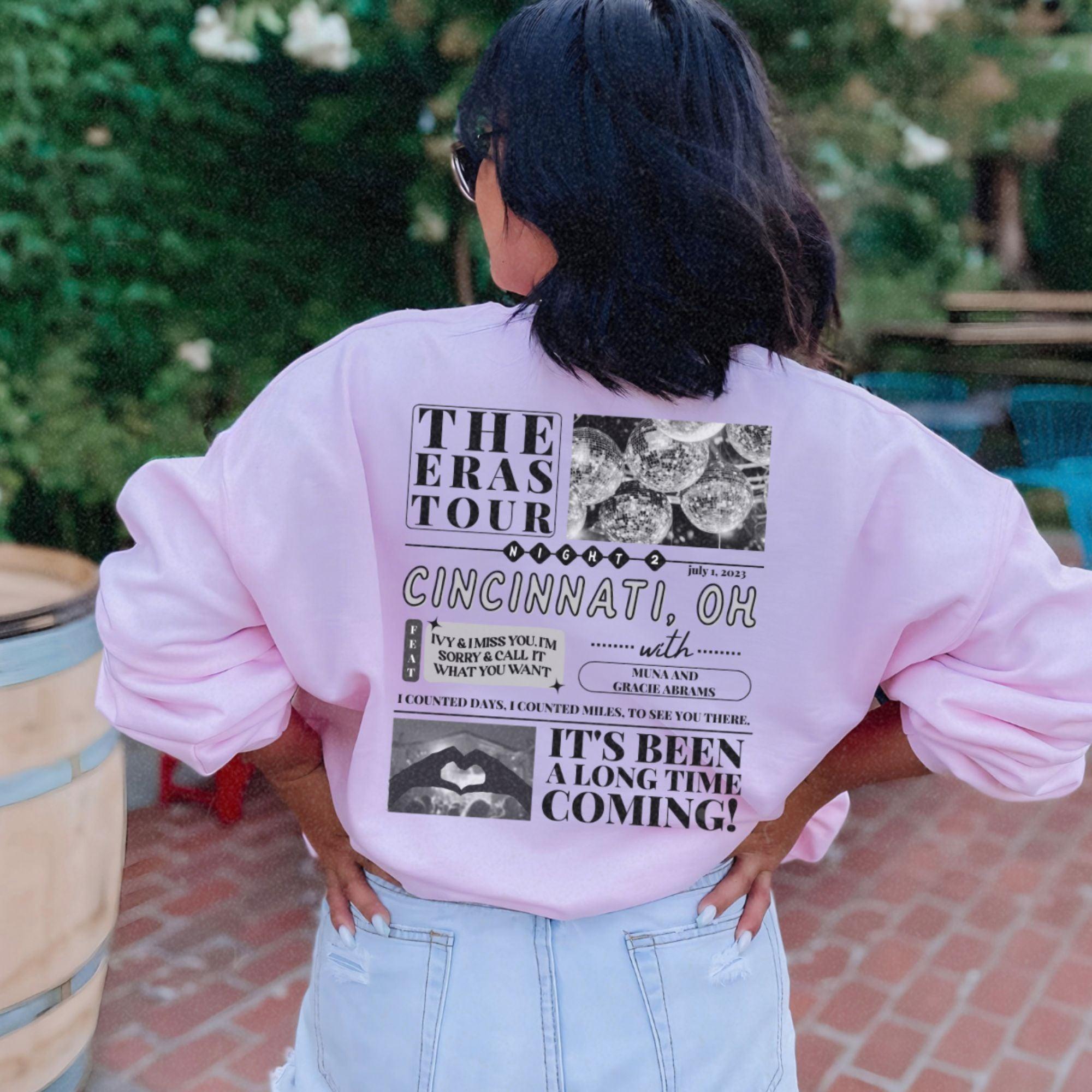 a woman wearing a pink shirt with a tour poster on it