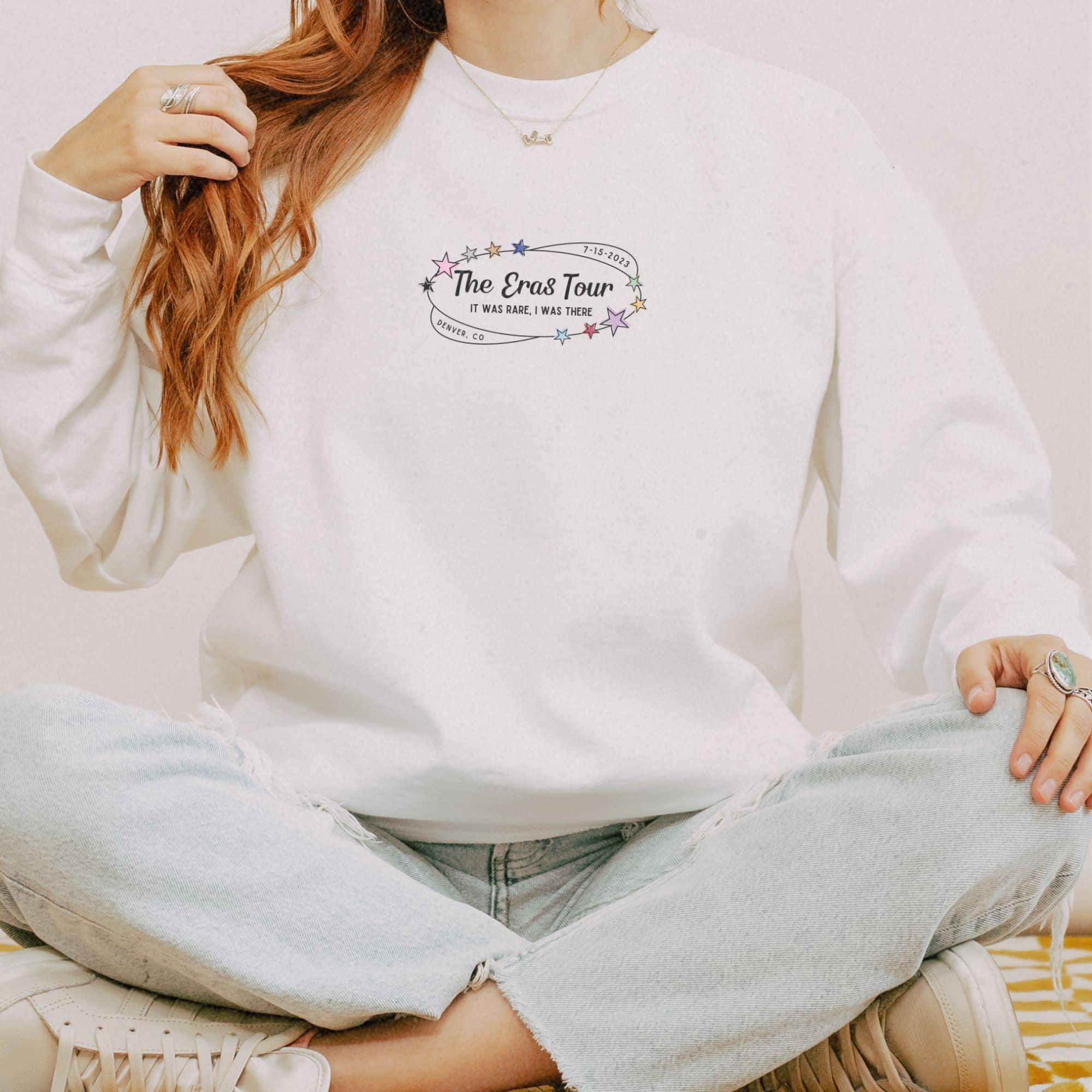 a woman sitting on the floor wearing a white sweatshirt