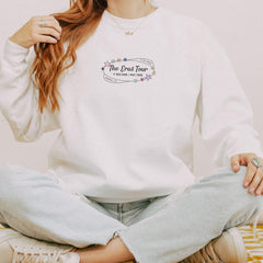 a woman sitting on the floor wearing a white sweatshirt