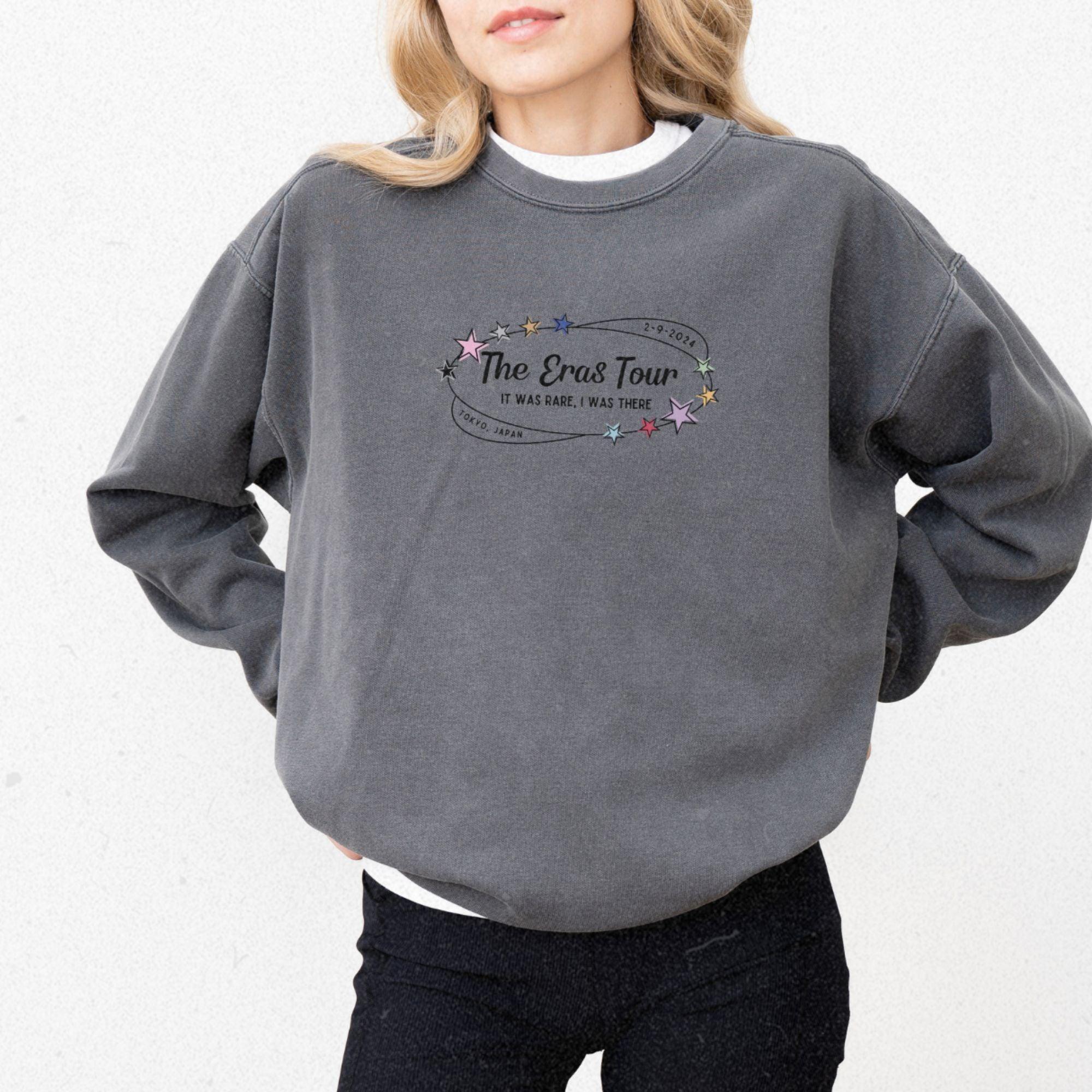 a woman wearing a grey sweatshirt with the words the great tour on it