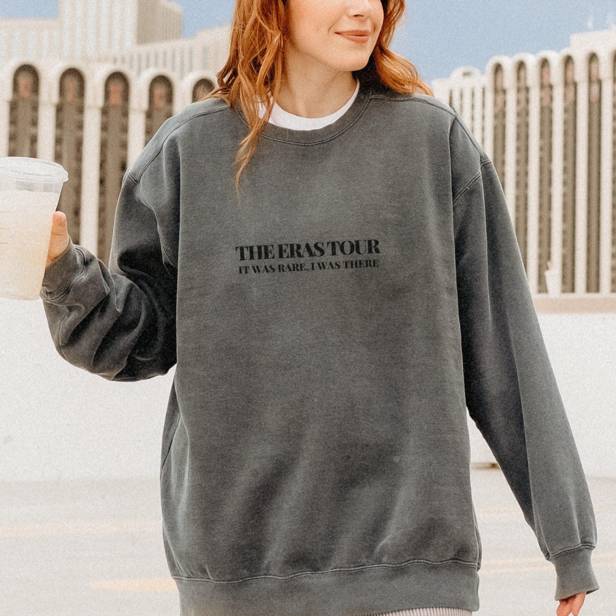 a woman in a sweatshirt holding a drink