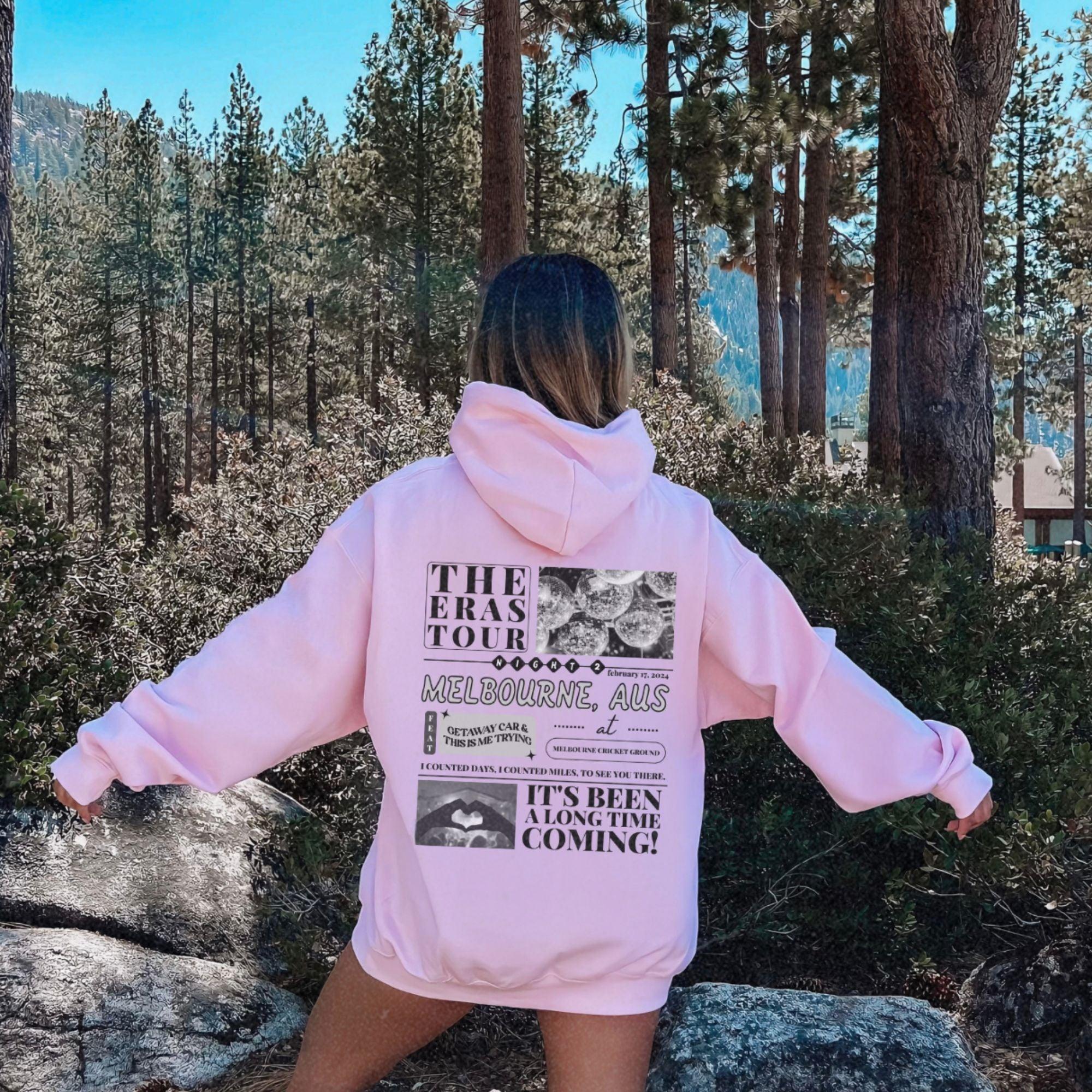 a woman in a pink hoodie is standing in the woods