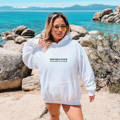 a woman in a white hoodie standing on a beach