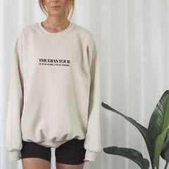 a woman standing in front of a plant wearing a sweatshirt