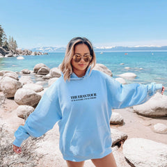 a woman standing on a beach wearing a blue sweatshirt